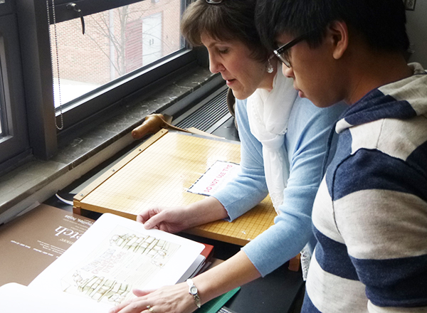 Cheryl Sheeler showing her portfolio to senior Arren Dawinan.
