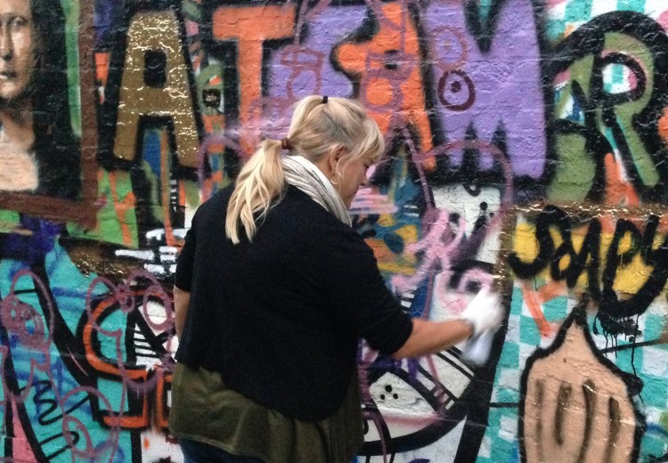 Kathy Sue Traylor tagging the wall in graffiti alley.